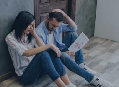 two people sitting, seemingly stressed while looking at a document